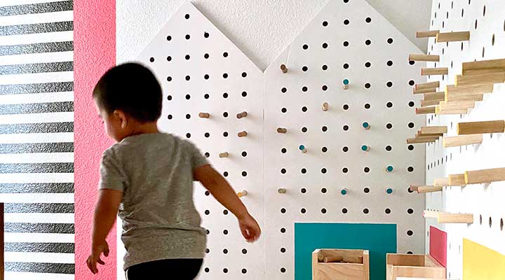 Toddler runs past toy storage pegboard walls